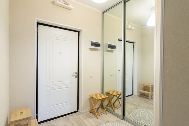 Entrance hall interior with metal front door and large sliding wardrobe with mirrors
